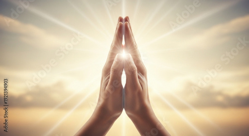 Hands together in prayer with divine light and sun rays symbolizing hope and spirituality in a serene atmosphere