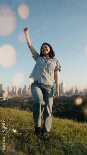 Woman celebrating in green field cityscape.