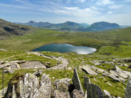 Fotografia A Stunning Glacial Lake Nestled in a Lush Green Mountain Valley