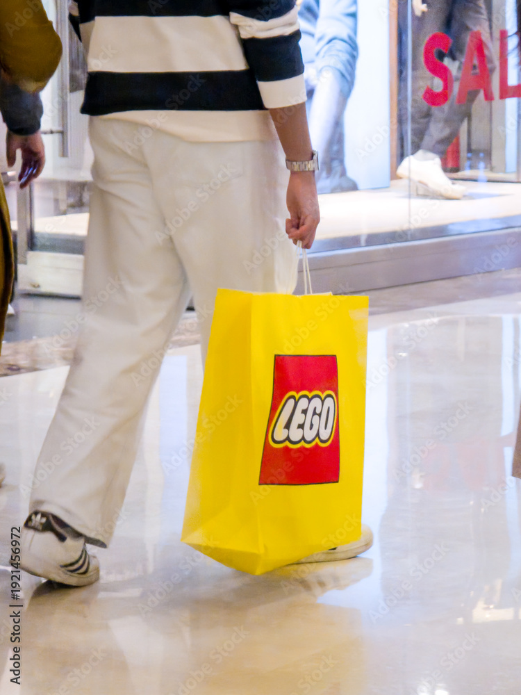 Fototapeta premium Customers carrying the iconic yellow and red themed LEGO bag from India's first store in ambience mall showing the popularity of this toy