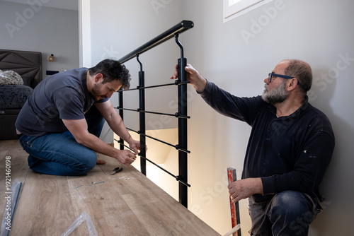 Men installing a black metal safety handrail for home renovation or construction project