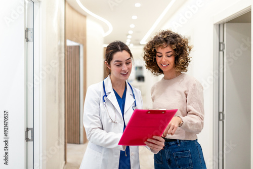 Canvas-taulu A smiling female doctor shows positive medical results on a red clipboard to a happy patient