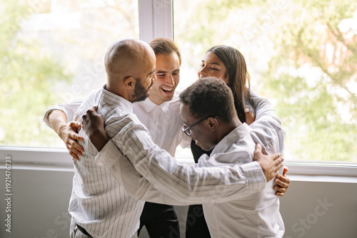 Diverse team hugging each other in celebration of a successful project. They are all smiling and laughing, happy to be together