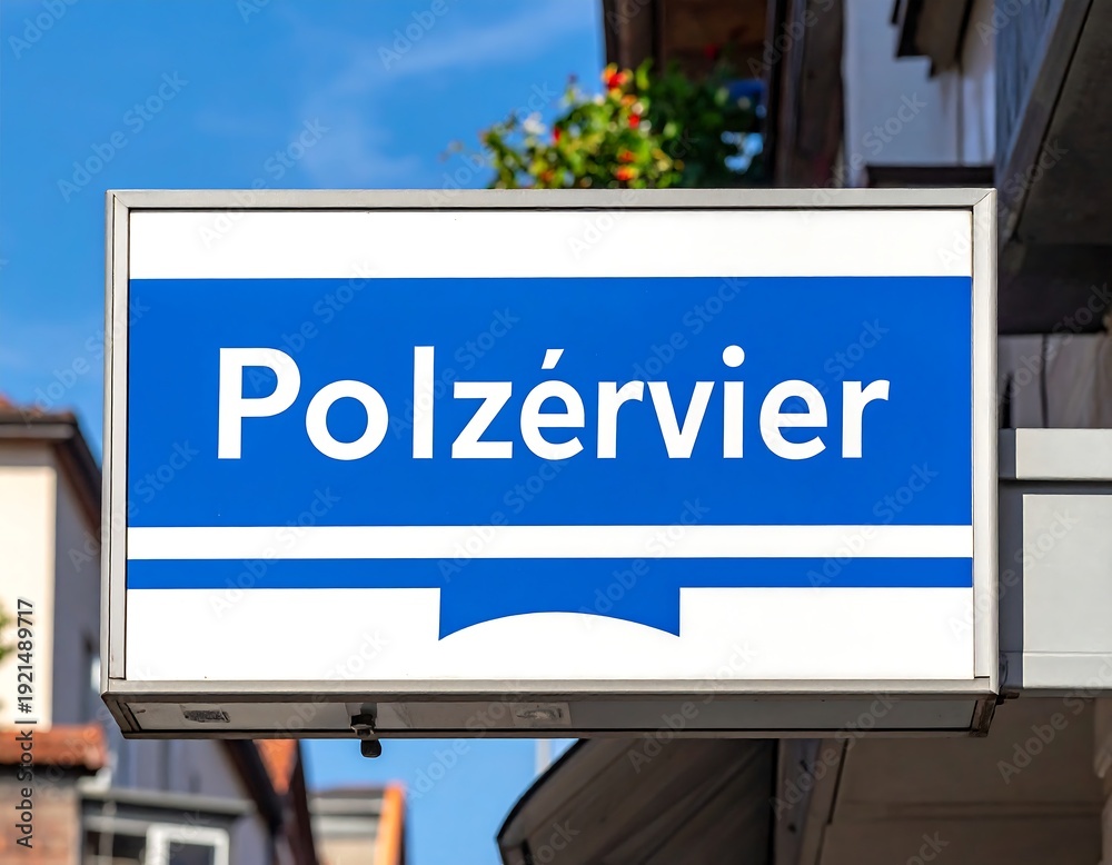 Obraz premium Rectangular blue-on-white shop sign against a bright sky