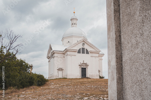 Isolated view of the white baroque Saint Sebastian Chapel on the grassy top of Holy Hill in Mikulov during a cloudy day