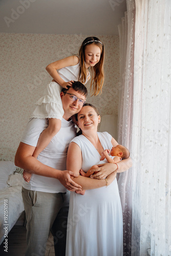 Family poses with newborn and sibling indoors