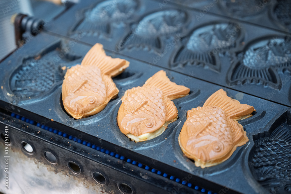 Fototapeta premium Taiyaki cooking on a traditional grill in Japan, close up of street food