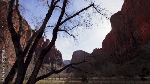 View from the vehicle driving down Zion canyon of Angels Landing as the sun peaks over the cliffs in Utah.
