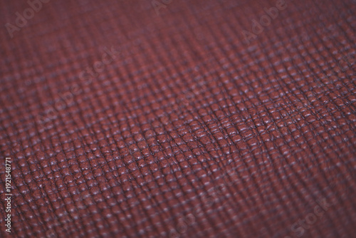 Abstract macro photography of a dark burgundy brown textured surface, resembling faux leather or woven cover material, with a shallow depth of field.