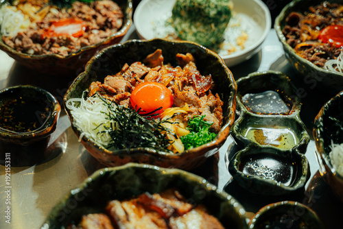 Close-up of a traditional Japanese beef rice bowl (donburi) topped with fresh raw egg yolk, shredded nori seaweed, green onions, and caramelized onions. Served in a rustic ceramic bowl with grilled po