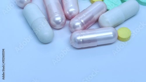 Video 4k footage. Arc Shot close-up of pink capsules yellow and green tablets on white background