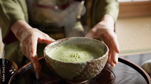 Matcha tea served in ceramic bowl with textured surface, warm green color, and steam rising