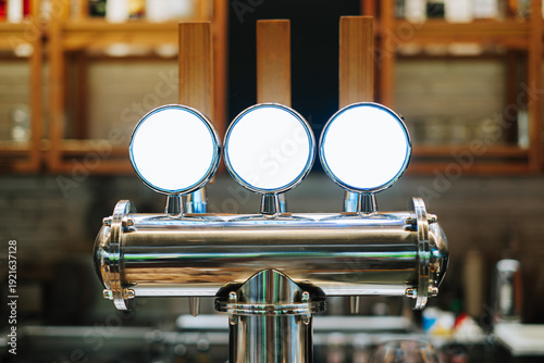 Bild auf Leinwand Three polished chrome draft beer or nitro cold brew taps with blank white labels