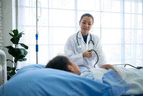 фотографія Doctor preparing blood pressure monitor for young inpatient in hospital ward