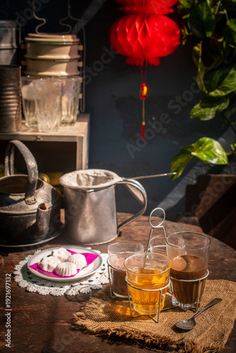 Photography Vintage Southeast Asian coffee set with metal kettle, cloth filter, and glass cups in a rustic cafe atmosphere
