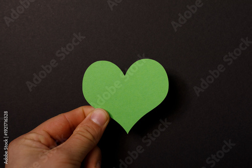 A hand holds a green heart-...