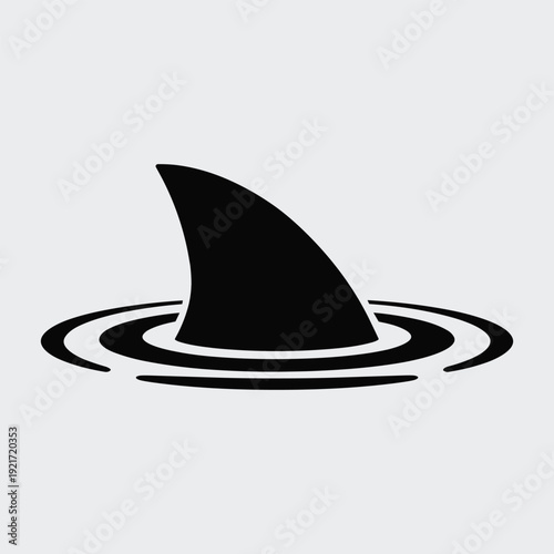 Dramatic shark fin emerging from water with ripples