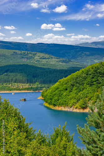 Panoramic landscape of Lake Zavoj surrounded by forested hills and mountains near Pirot in southeastern Serbia under blue sky