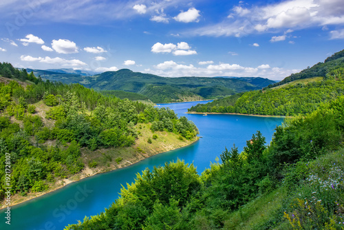 Panoramic landscape of Lake Zavoj surrounded by forested hills and mountains near Pirot in southeastern Serbia under blue sky