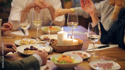 Group of elegant senior friends dining and socializing together. Mature people enjoy appetizers and wine during a cozy evening at home