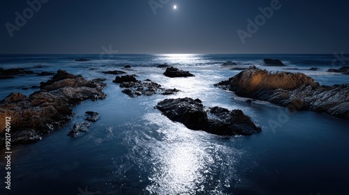 Bright moon illuminates dark ocean waves crashing around coastal rock formations at night