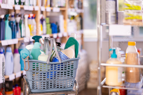 Photos Shopping basket full of essential cleaning products, detergents, sprays, scrubbing tools and personal care products, ideal for home maintenance and hygiene displayed in store for purchase
