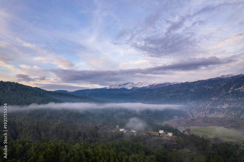Obraz premium A stunning drone perspective of Çaltepe village on the St Paul Trail, showcasing the harmony between traditional rural life, green agricultural fields, and the dense pine forests covering the rugged s