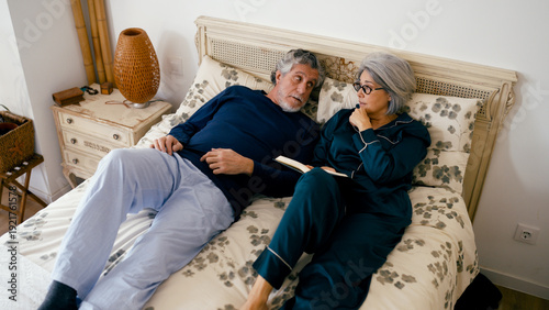 Tableau sur toile Senior couple relaxing in bed, wearing pajamas and talking