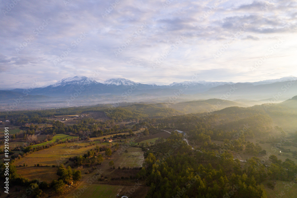 Naklejka premium A stunning drone perspective of Çaltepe village on the St Paul Trail, showcasing the harmony between traditional rural life, green agricultural fields, and the dense pine forests covering the rugged s