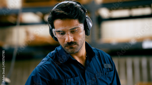 Man focusing on his work, wearing safety glasses and ear muffs for protection in a woodworking workshop