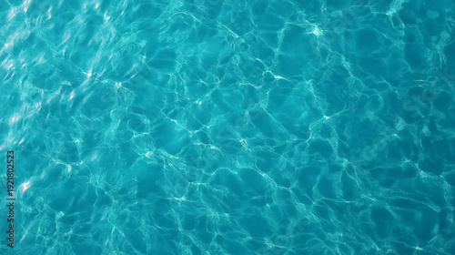Clear turquoise water with sunlight reflecting, creating shimmering patterns and ripples on the surface.