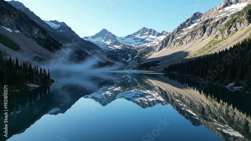 Scenic view of tranquil lake reflecting majestic mountains and lush evergreen trees under clear blue sky, showcasing nature's beauty in a serene outdoor setting
