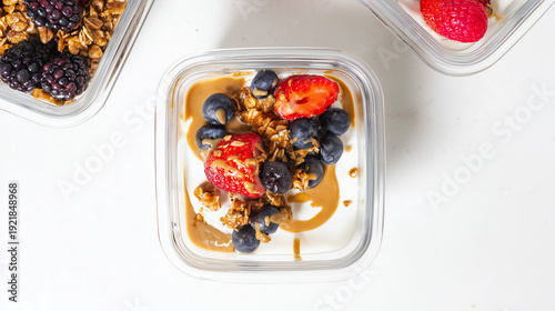 Top view of yogurt parfait with strawberries, blueberries, granola and peanut butter drizzle in glass container. Healthy breakfast or snack concept.