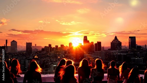 Silhouettes of a crowd of people watching a dramatic sunset over a city skyline from a rooftop. Group of friends enjoying a golden hour evening party. Urban lifestyle and celebration concept