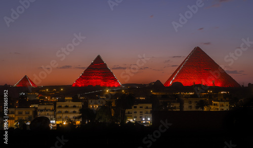 Φωτογραφία Silhouettes of the Giza Pyramids towering over the rooftops of Cairo at sunset
