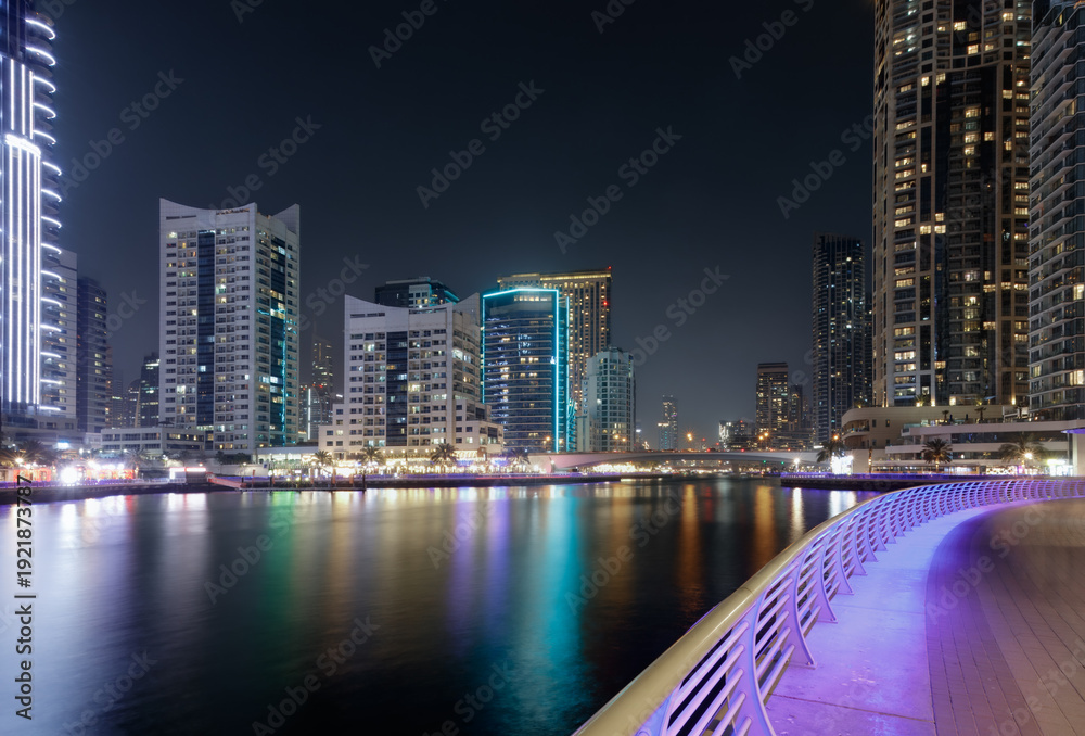 Fototapeta premium Deep neighborhood imprint skyline perspective wide canal framed by Dubai Marina residential towers and electric reflections at night for authentic metropolitan tourism and regional city branding.