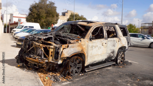 Burnt-out car accident city houses in the parking lot near the houses.