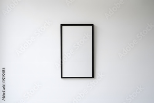 A blank black picture frame hanging on a white wall