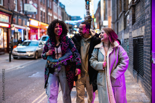 Diverse friends laughing walking city street evening carrying roller skates