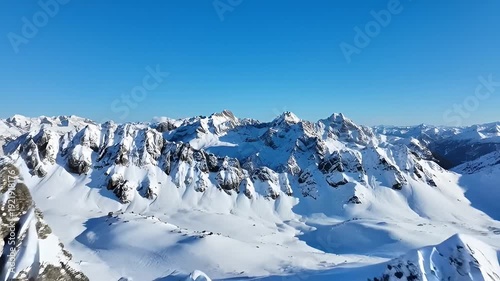 Magnificent aerial view of snow covered mountain range against a vibrant blue sky