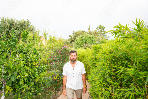 Bearded man walking in lush green garden path, peaceful outdoor lifestyle and connection with nature