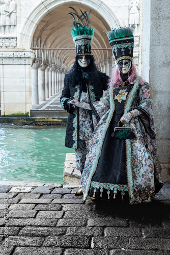 Elegant Masked Couple in Period Costumes by the Canal During Venice Carnival