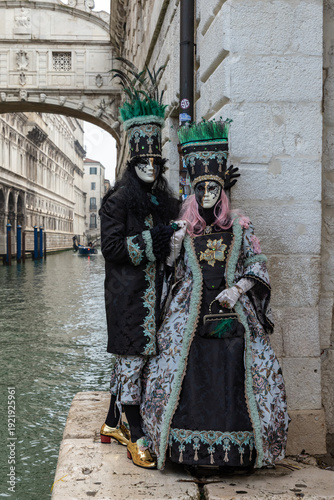 Elegant Masked Couple in Period Costumes by the Canal During Venice Carnival