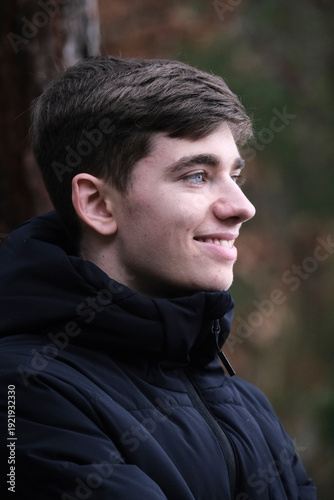Male in black winter jacket. Smiling young guy. Winter forest	
