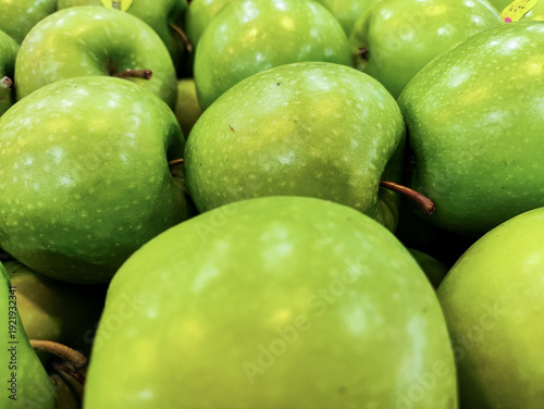Close-up of fresh green Granny Smith apples at a local grocery market. These organic tart fruits are harvested for their crunchy texture, providing a healthy, vitamin-rich snack for a balanced diet.