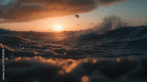 Kitesurfer riding ocean waves during a vibrant sunset over a coastal area.