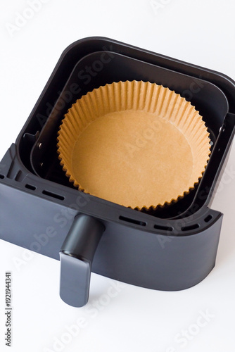 Disposable, non-stick, round air fryer's wax paper lines in air fryer basket on white background