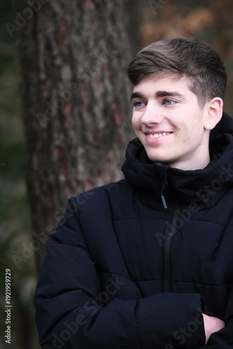 Male in black winter jacket. Smiling young guy. Winter forest	

