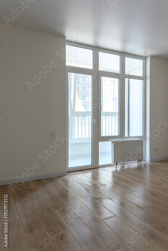 Bright empty room with large windows and wooden flooring, modern design