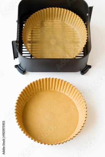 Disposable, non-stick, round air fryer's wax paper lines in air fryer basket on white background